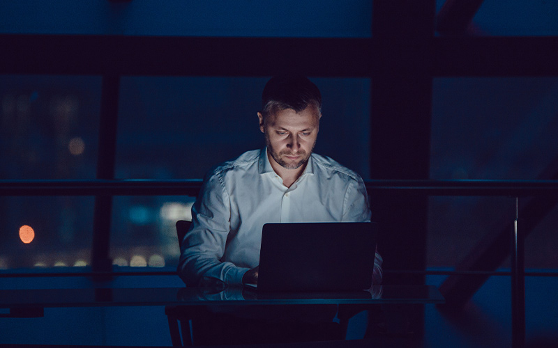 Een man werkt 's nachts op zijn laptop