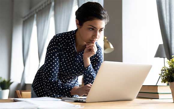 Een vrouw kinkt bedenkelijk naar haar laptop