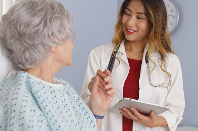 Een verpleegster met een tablet bij een patient