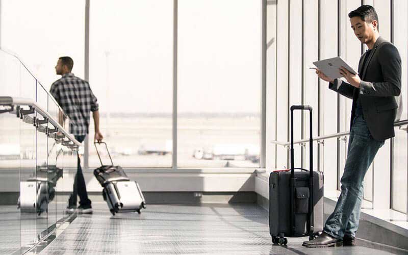Een zakenman met een Microsoft Surface laptop bekijkt zijn mail op het vliegveld
