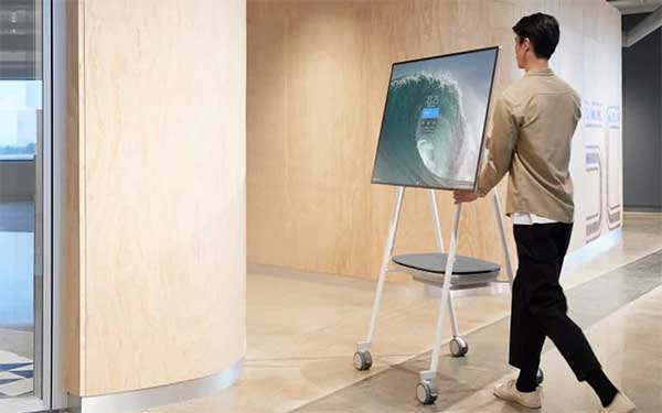 Een man verplaatst een Surface Hub 2S op een mobile stand