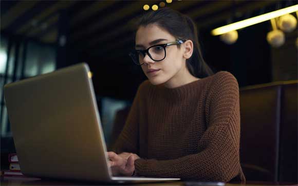 Een jonge vrouw zit achter haar laptop