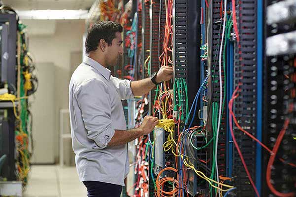 Een man werkt aan een patchkast in een datacenter