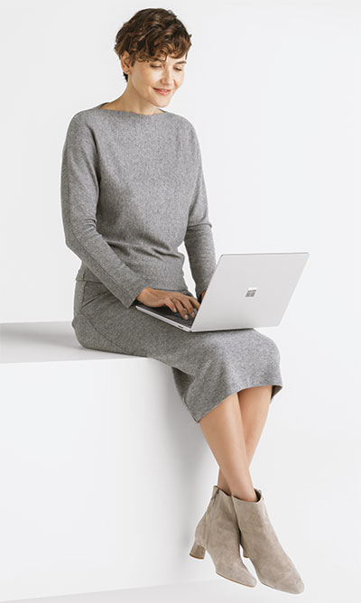 Een zitende vrouw met een Surface Laptop 6