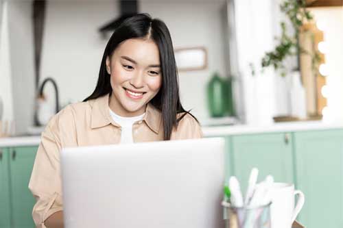 Een jonge aziatische vrouw werkt op een laptop