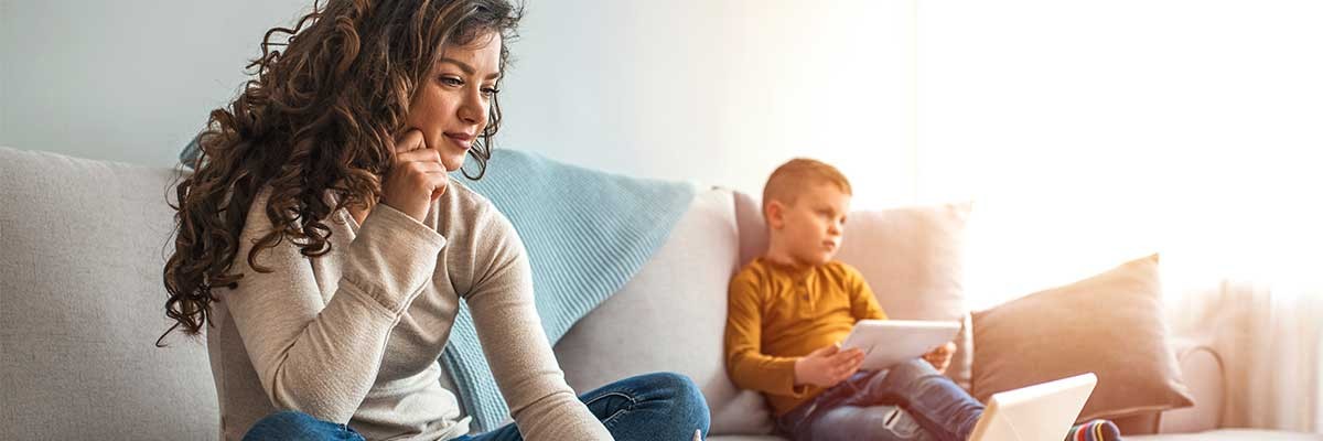 Een vrouw werkt vanuit huis met haar kind op de bank