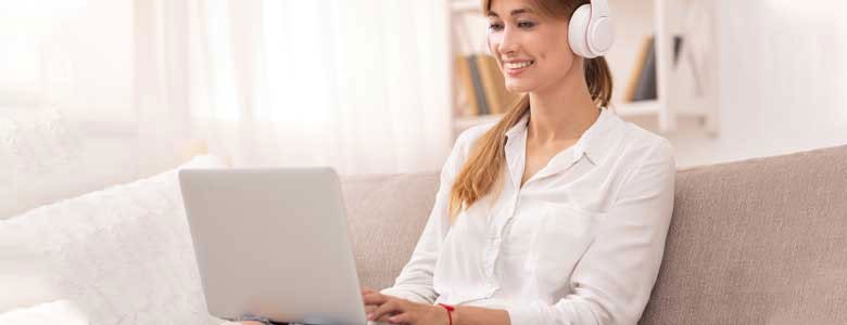 Een vrouw op de bank met laptop en koptelefoon