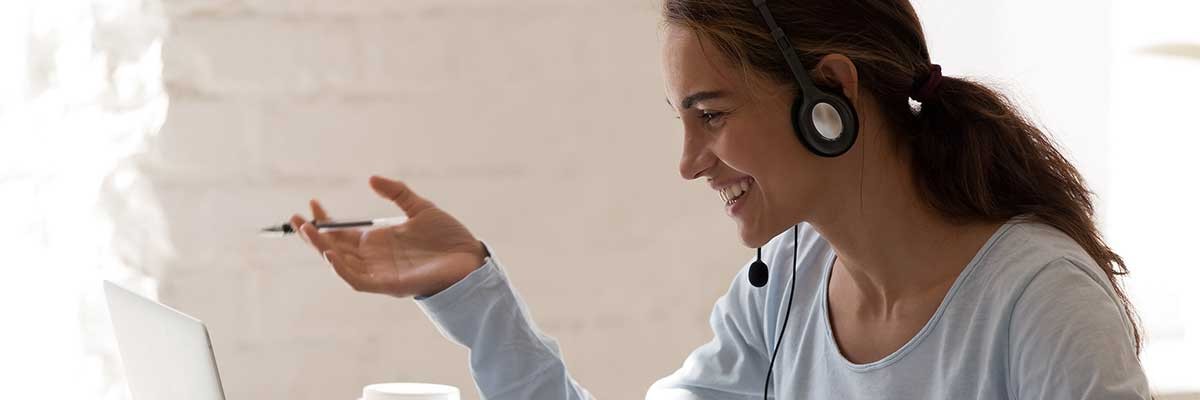 Een jonge vrouw vergadert via haar laptop met een hoofdtelefoon