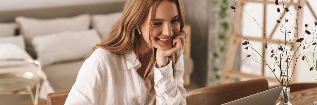 Een vrouw lacht terwijl ze op haar laptop werkt