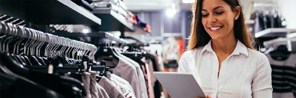 Een eigenaresse van een kledingwinkel bekijkt reak-time data op haar tablet