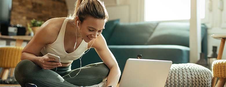 Een jonge vrouw volgt sportlessen via haar laptop