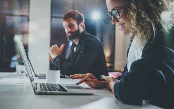 Een vrouw werk lachend achter haar laptop