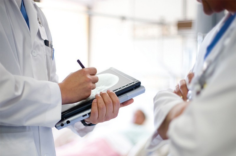 Twee artsen bekijken een patientdossier op een 2-in-1 laptop