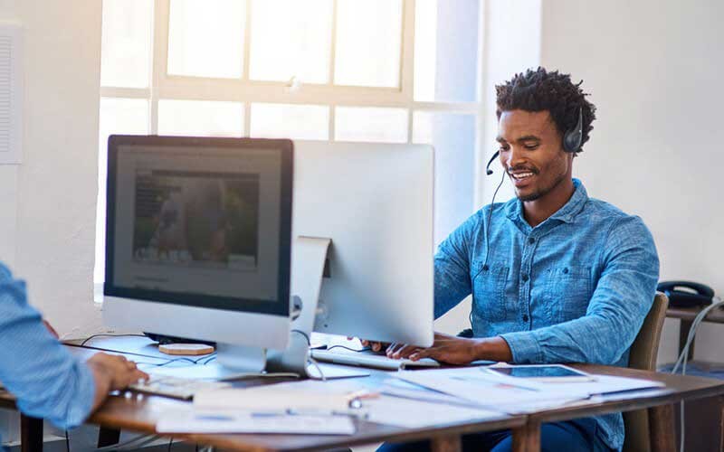 All-inclusive ondersteuning Een man met UC-headset werkt achter zijn monitor.