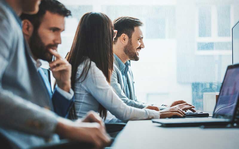 Vier collega's achter hun bureau