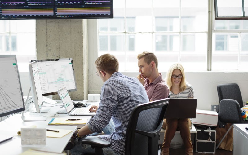 Medewerkers die samenwerken in een kantoor met desktop- en laptopapparatuur