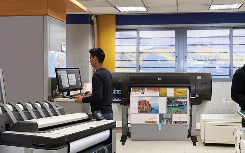 Een  man stuurt prints naar een HP DesignJet printer
