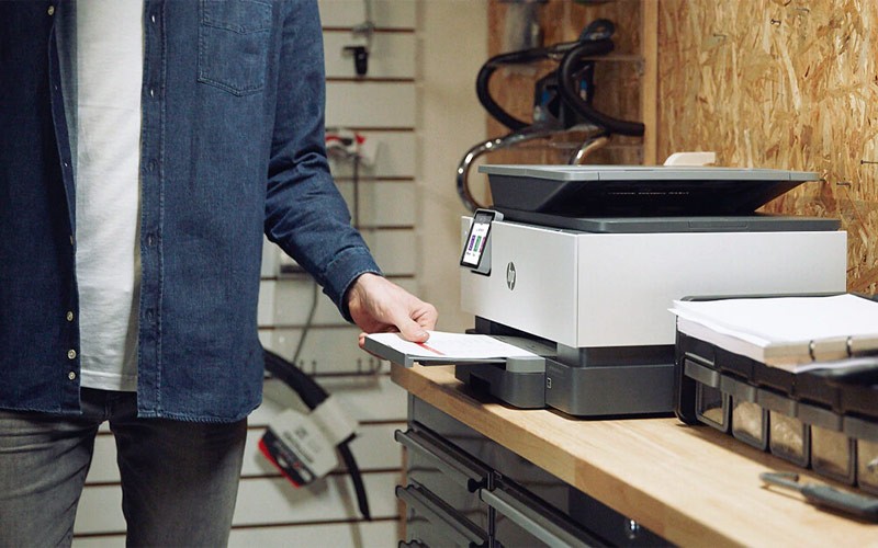 Een man haalt prints uit een HP OfficeJet