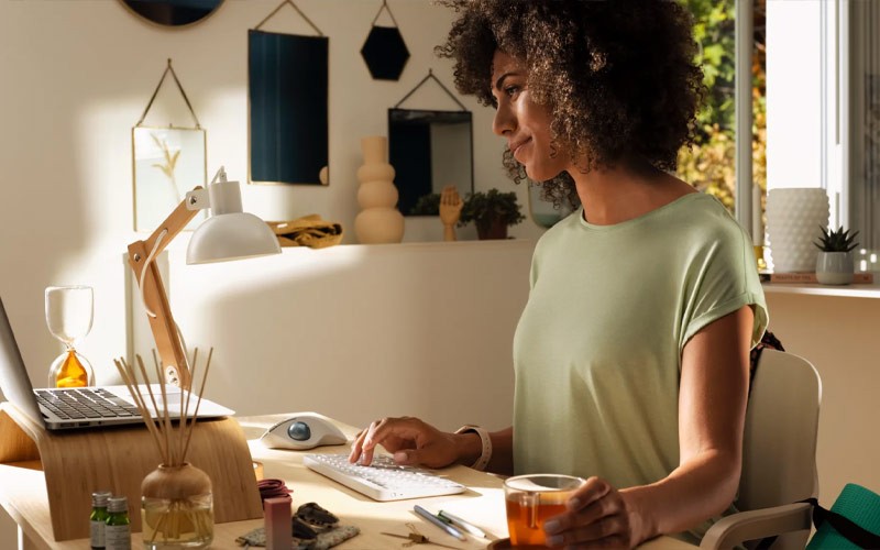 Een vrouw werkt vanuit huis met ene Logitech keyboard en trackball muis