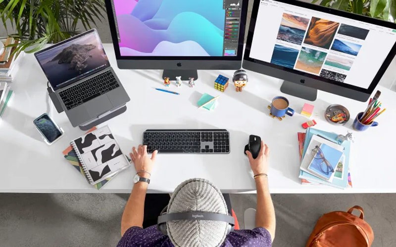 Een ontwerper werkt op zijn laptop met een Logitech muis