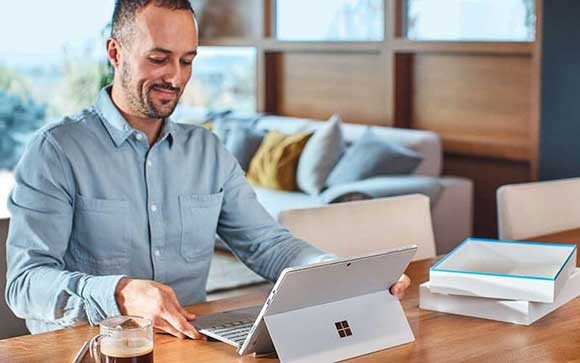 Een man opemt zijn Surface laptop en gaat aan het werk
