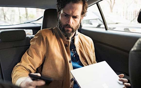 Een man gebruikt zijn Microsoft Surface laptop in een auto