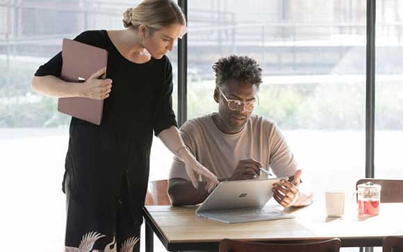 Een jonge man en vrouw gebruiken Microsoft Surface laptops