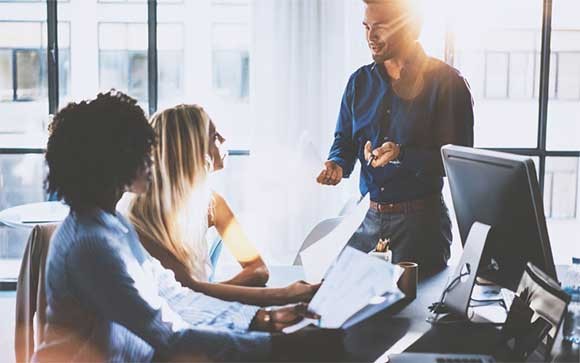 Een man is in gesprek met twee vrouwlijke collega's