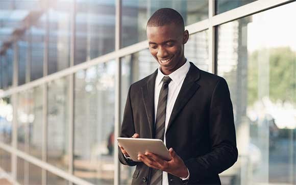 Een zakenman lacht terwijl hij zijn tablet buiten gebruikt