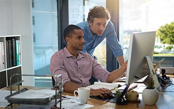 Twee collega's bekijken content op een iMac