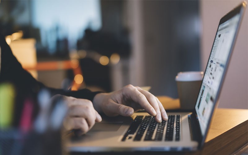 Een man typt op zijn laptop