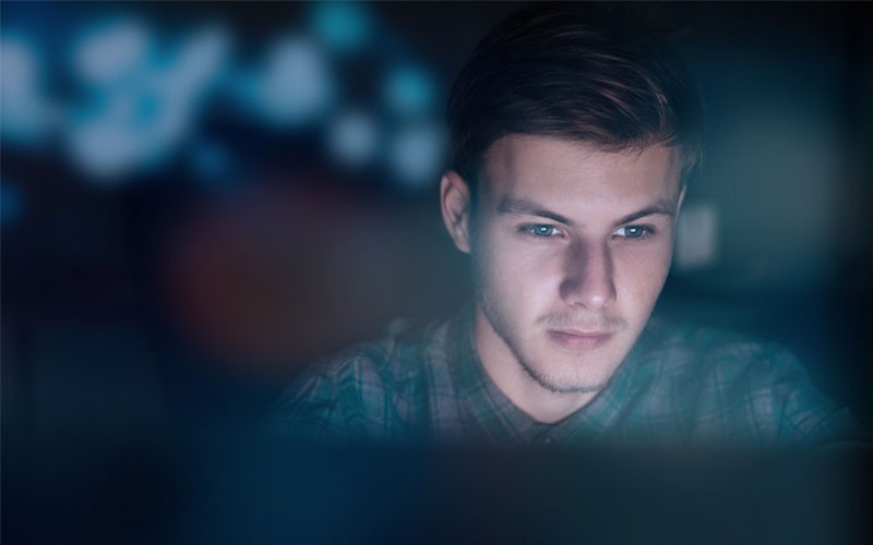 Een jonge man werkt 's nachts op zijn laptop