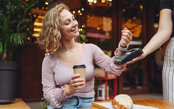 Maak indruk op uw klanten met slimme ervaringen Een vrouw betaald met haar smartwatch